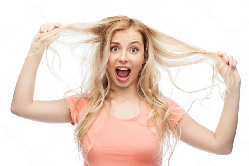 Woman in the UAE holding strands of falling hair with a shocked expression